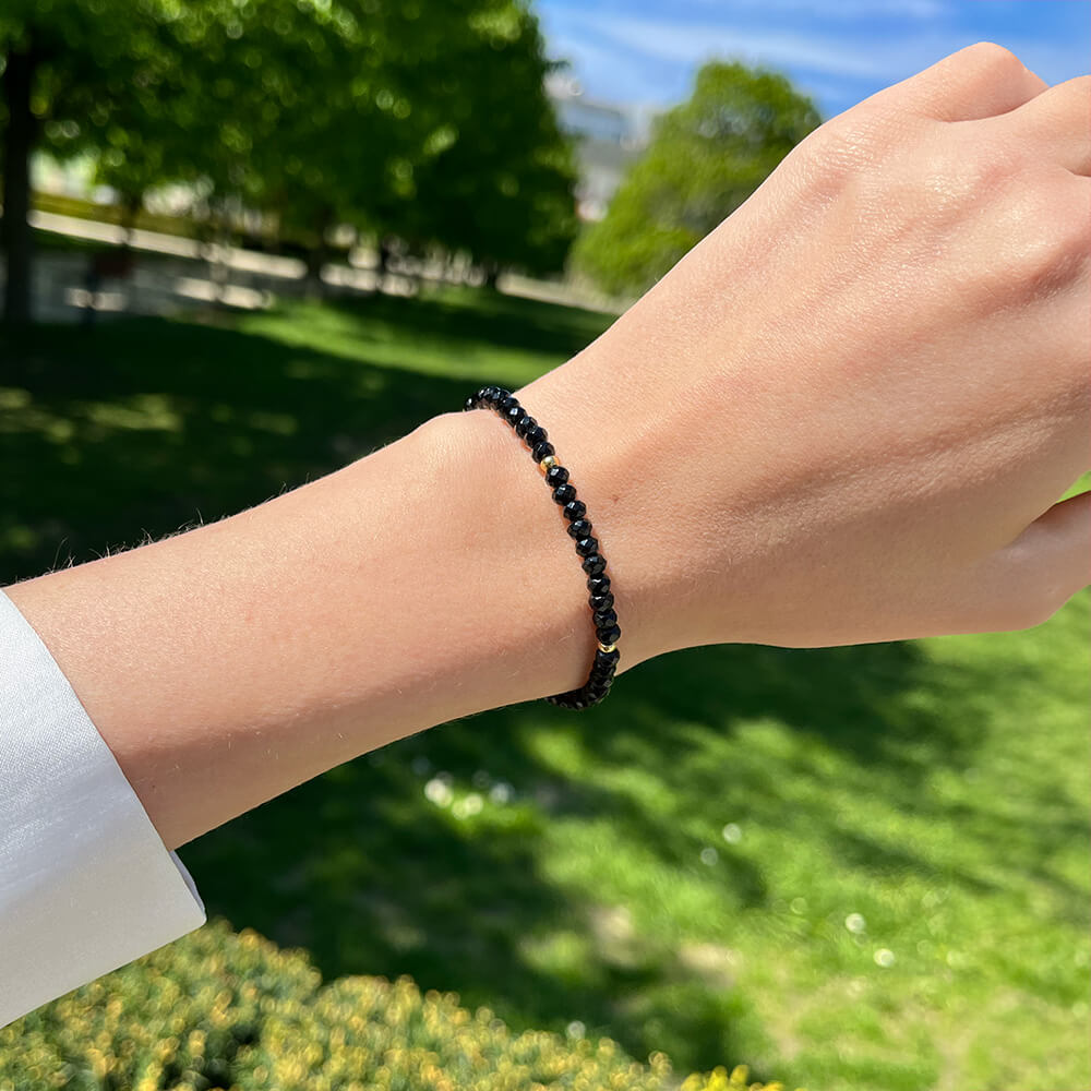 Minimalistický náramok Black Onyx s pozlátenými detailmi na ruke ženy.