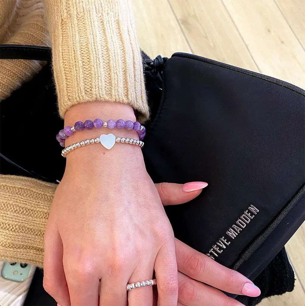 Ručne vyrábané náramky princess a fialový Rapunzel na ženskej ruke. V zábere aj kabelka steve madden.