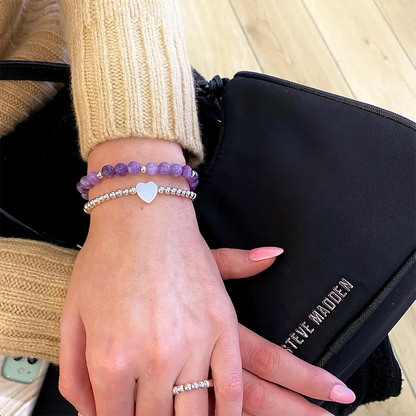 Ručne vyrábané náramky princess a fialový Rapunzel na ženskej ruke. V zábere aj kabelka steve madden.