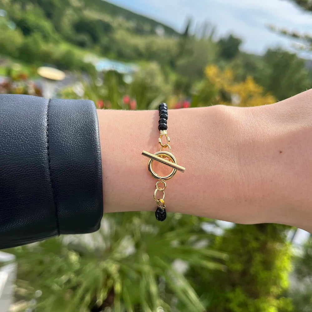 Elegantný dámsky náramok Black Onyx s pozlátenými detailmi na ruke mladej ženy.