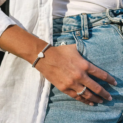 Minimalistický prsteň Princess's/Queen's Ring na ženskej ruke, kombinovaný s náramkom pre dokonalú harmóniu.